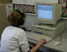 A student training on an early classroom computer with headphones